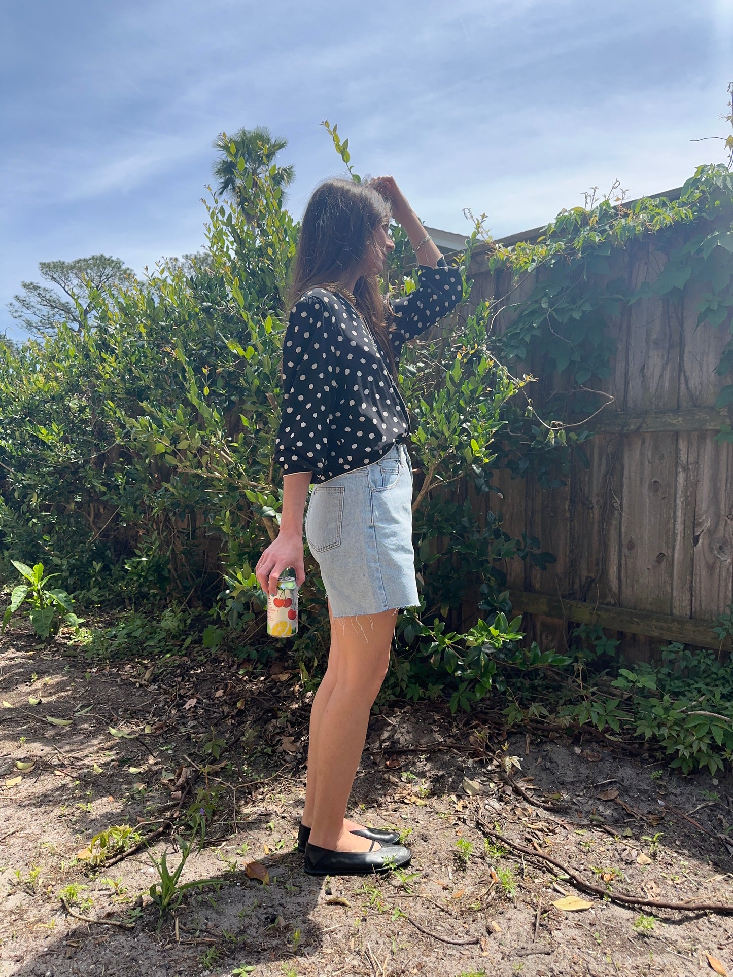 Girl standing wearing vintage polka dot blouse, retro wrap blouse. 