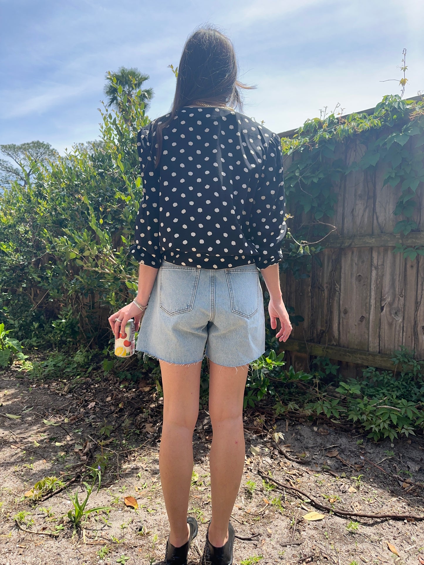 Girl standing wearing vintage polka dot blouse, retro wrap blouse. 