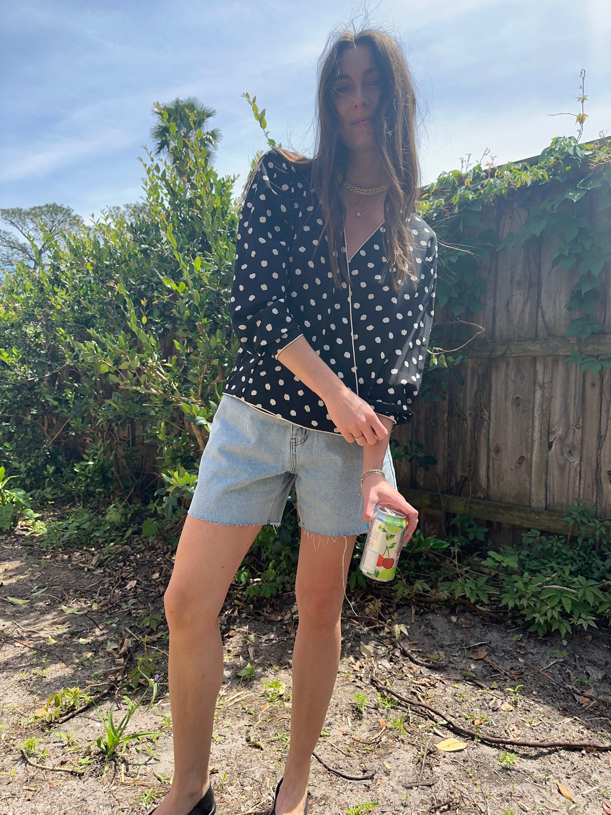 Girl standing wearing vintage polka dot blouse, retro wrap blouse. 