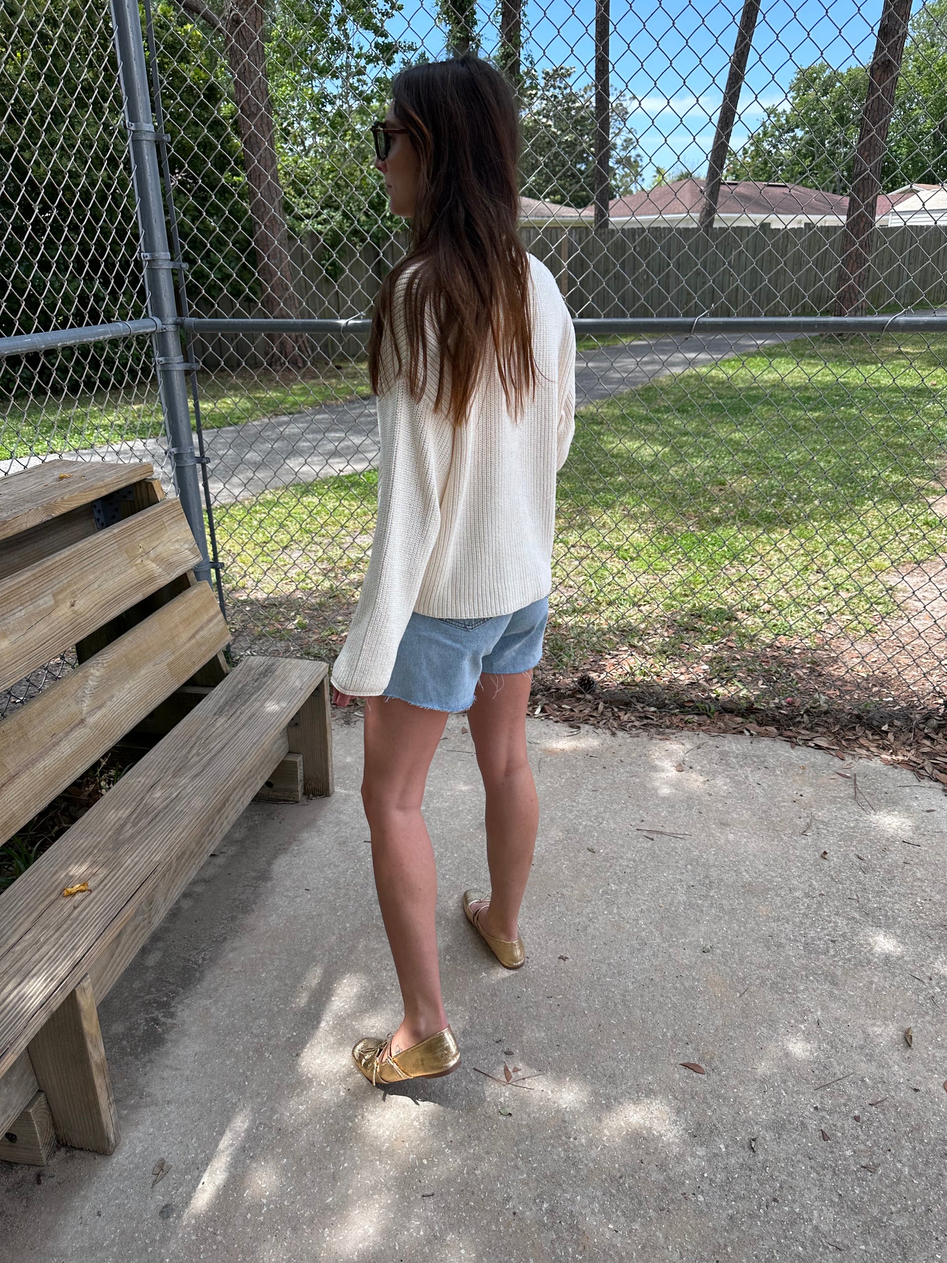 Woman wearing chunky cocoon cardigan, Ivory knit cardigan sweater and seashell necklace holding a coffee.