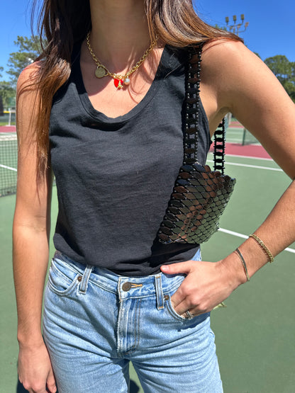 Woman in American Vintage Clothing tank top wearing gold charm necklace and vintage beaded shoulder bag. 