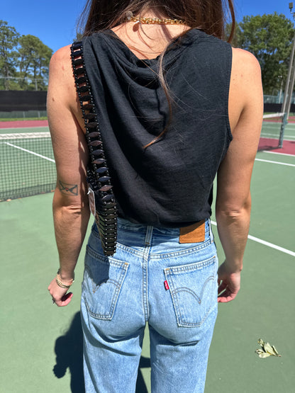 Woman in American Vintage Clothing tank top wearing gold charm necklace and vintage beaded shoulder bag. 